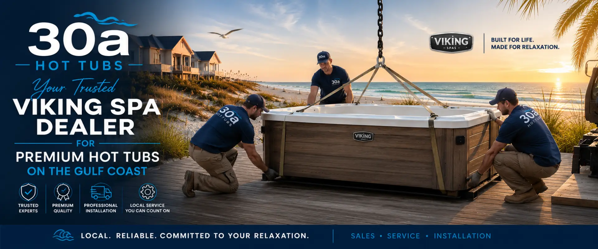 Three crew members in blue shirts secure a wooden Viking Spa hot tub on a dock at sunset by the beach, with houses and palm trees in view.